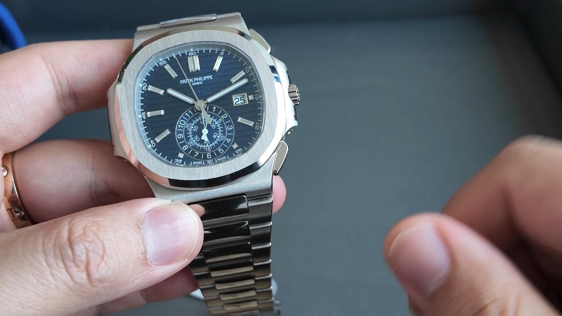 Patek Philippe Nautilus 5976/1G-001 cầm trên tay, phía sau là mẫu đồng hồ vỏ vàng đồng hành