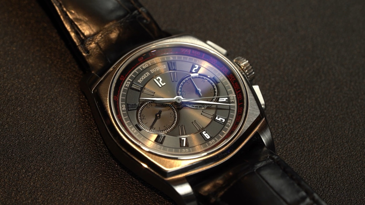 Mặt số Roger Dubuis La Monégasque DBMG0005 với ba bộ đếm và thang tachymeter đỏ trong video Gia Bảo