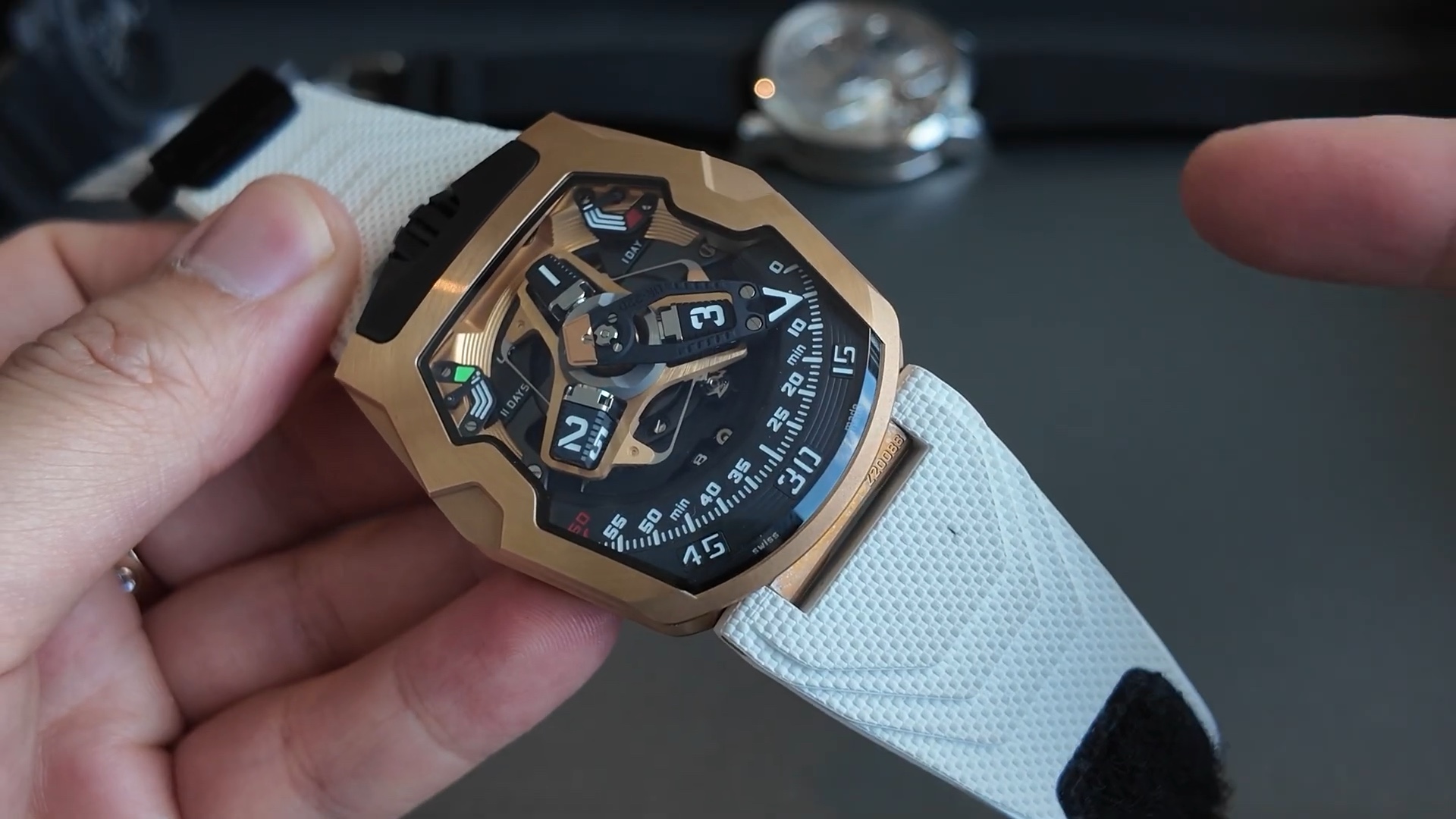 Cạnh vỏ vàng đỏ 4N của Urwerk UR-220 cầm trên tay, kích thước 52.9 x 43.8 mm