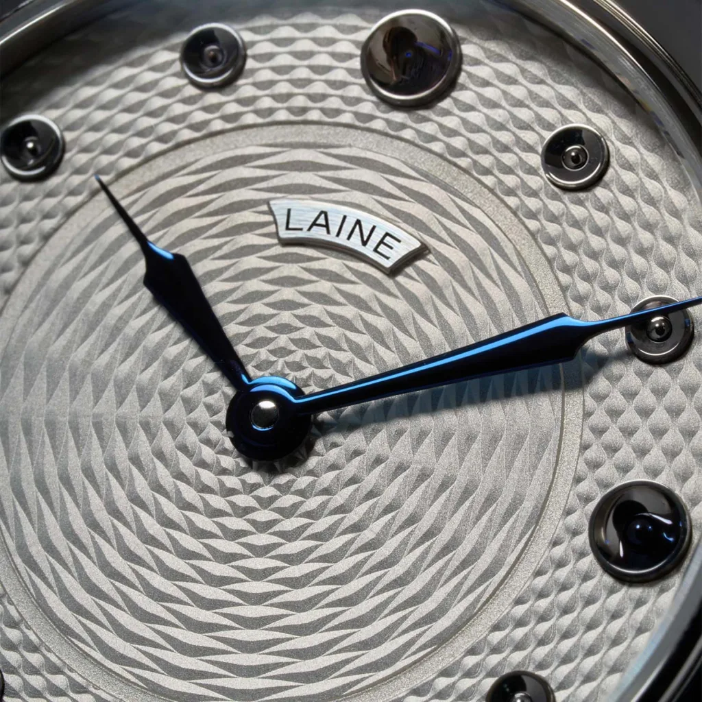 Cận cảnh guilloché, kim xanh và cọc giờ lõm trên Laine P33