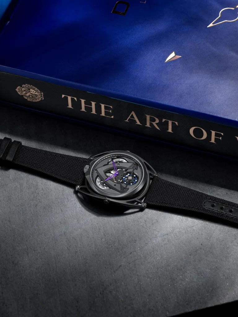De Bethune DB28xs Dark Sand đặt cạnh một cuốn sách nghệ thuật