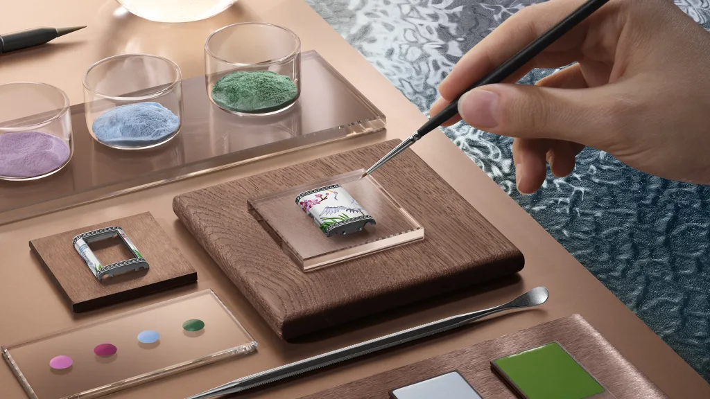Bút mảnh hướng vào phần vỏ Reverso One Sakura vẽ chim hạc và hoa anh đào bên các lọ màu