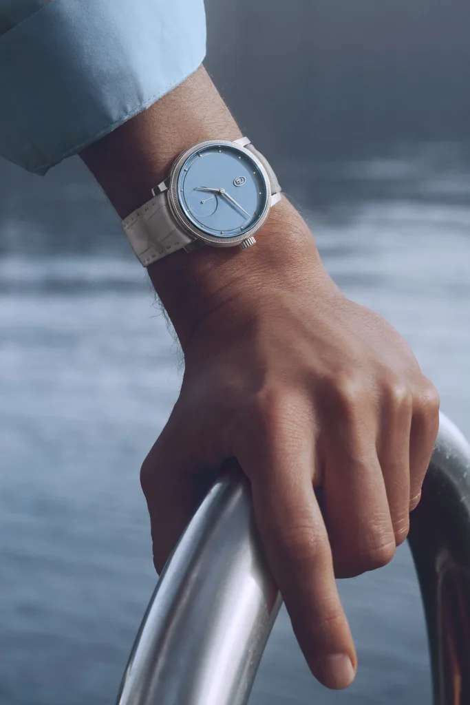 Toric Morning Blue trên cổ tay với tay áo xanh sáng và dây da xám trong bối cảnh đời thường